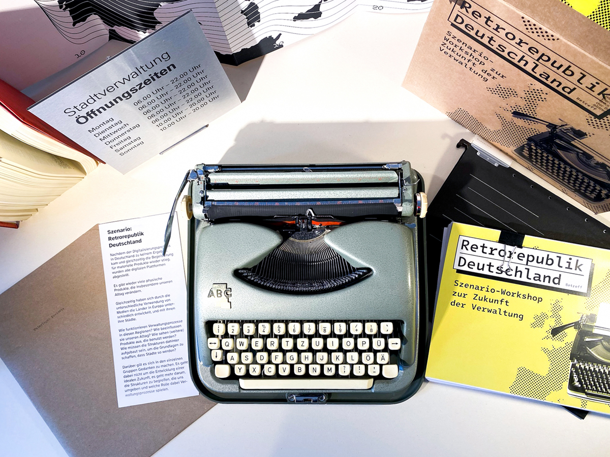 Eine Schreibmaschine, ein Schild mit Öffnungszeiten, und Unterlagen.